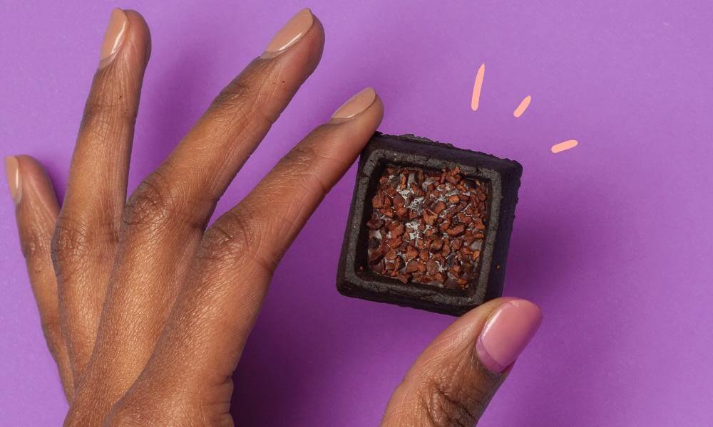 Hand holding a triple chocolate cookie square with dark chocolate ganache.